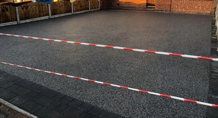 Resin Bound A flat, gravelled area with a red and white barrier tape marking boundaries.