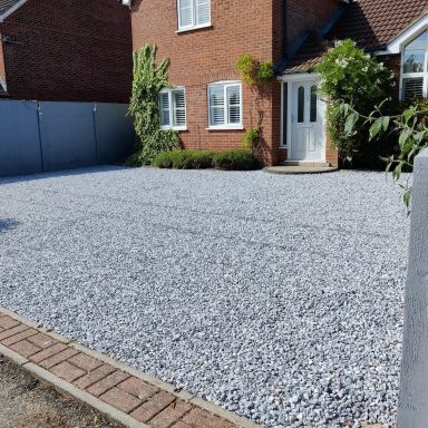 Gravel Driveway Gravel driveway in front of a brick house with a white door and green plants.
